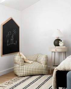 a bedroom with a chalkboard on the wall next to a chair and rug in front of it