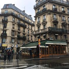 people are walking in the rain near some buildings