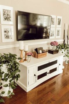 a flat screen tv mounted on the wall above a white entertainment center in a living room