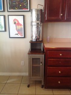 a blender sitting on top of a wooden cabinet next to a wall with pictures