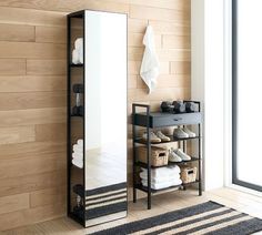 a mirror and shelf with shoes on it in a room that has wooden walls, wood flooring, and a striped rug