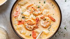 a bowl of soup with shrimp and dumplings on the side next to a spoon