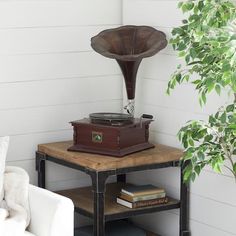 an old record player sits on top of a table next to a white chair and potted plant