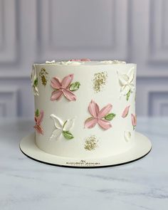 a white cake with pink and green flowers on it