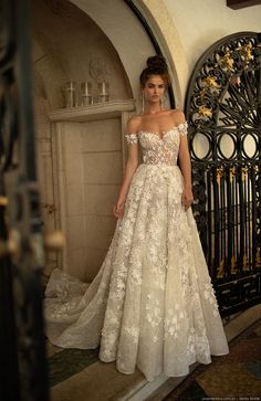 a woman standing in front of a gate wearing a wedding dress