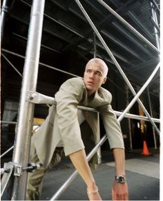 a man leaning on the side of a metal structure with his foot propped up against it