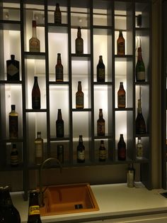 a kitchen counter topped with lots of bottles next to a sink under a light fixture