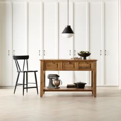 a wooden table sitting next to two stools in front of a wall with white paneling