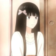 a girl with long black hair wearing a white shirt and bow in front of an open door