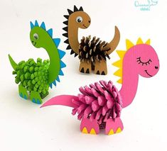 three paper dinosaurs with pine cones on their heads and one dinosaur holding a pine cone