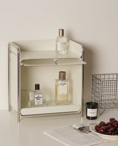 a white shelf with two bottles and some cherries on it next to an open magazine