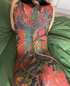 a woman laying on top of a green bed covered in lots of tattooed tattoos and flowers