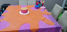 a purple and orange table with cupcakes on it in front of some chairs