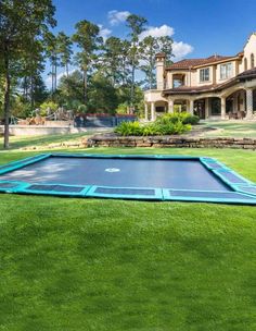 an inflatable trampoline is on the grass near a large house and trees