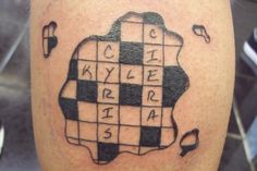 a man's leg with a crossword tattoo design on it, and the words written in cursive writing