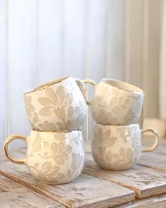 three white cups sitting on top of a wooden table