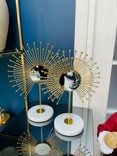 three gold and white vases sitting on top of a glass table next to a mirror