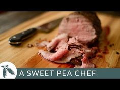 a piece of meat sitting on top of a wooden cutting board next to a knife