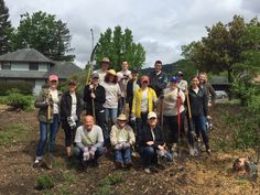 a group of people standing next to each other holding shovels and digging in the dirt