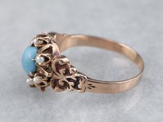 Completely original, A perfect robin's egg blue glass turquoise gleams from the center of this antique dinner ring. The mounting dates to the late 1800s, a distinctly Victorian style that is the perfect frame for the gorgeous glass gem!Metal: 14K Antique Rose GoldGem: Glass Turquoise Gem Measurements: 5.6 x 4.7 mm, OvalAccents: 6 Seed PearlsRing Size: 5.25 Antique Turquoise Ring For Anniversary, Antique Turquoise Cabochon Ring For Wedding, Antique Style Turquoise Wedding Ring With Cabochon, Vintage Turquoise Oval Cabochon Ring, 1800s Jewelry, Pearl Halo Ring, Pearl Halo, Dinner Ring, Turquoise Gem