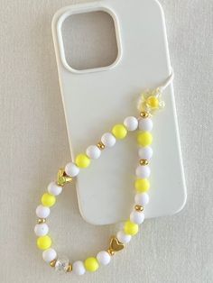 Beaded Phone Charm Wristlet, Iphone Strap -  White, Yellow and Gold design. Dress up your phone/tablet technology with a fun and stylish beaded hanger.  This stylish phone hanger has been made with a durable white cord so you wont have to worry about it breaking!  Customise your hanger with a name, nickname, or phrase. [examples shown in some listings], or it can be created as is. If personalising with a name this comes in WHITE/GOLD beads. This phone hanger is made with acrylic, metal & matte beads.  Gift boxing available Size when attached to phone is approx 20cm Phone Hanger Beads, Beaded Hanger, Phone Hanger, Phone Cords, Phone Wristlet, Phone Plug, Iphone Design, Phone Strap, Design Dress