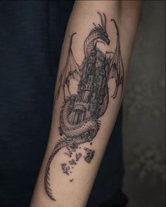 a black and white tattoo of a dragon on the arm with a castle in the background