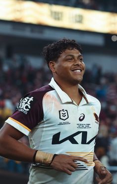 a man standing in front of a crowd wearing a white and maroon shirt with black writing on it