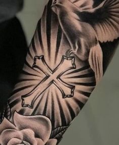 a person with a cross and dove tattoo on their arm, holding a rose in front of the cross