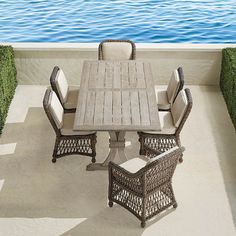 an outdoor dining table and chairs on a patio with water in the backround