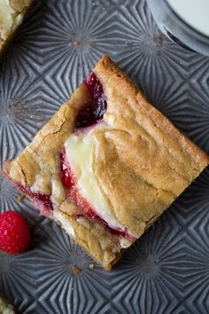 a piece of pie sitting on top of a plate next to a raspberry