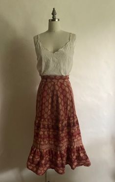 "1970s 100% cotton print skirt with drawstring at the waist and bottom hem ruffle was made in India. In excellent vintage condition. Waist up to 28\" Hips 38\" Length 29\":" Boho Skirt And Sweater Outfit, Vintage Long Gathered Skirt Bottoms, Vintage Long Gathered Skirt, Bohemian Skirt With Ruffle Hem, Vintage Cotton Flared Skirt Bottoms, Vintage Cotton Flared Skirt, Peasant Cotton Skirt With Ruffles, Vintage Flowy Maxi Skirt, Bohemian Long Skirt With Ruffle Hem