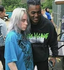 a man and woman standing next to each other in front of a chain link fence