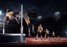 a group of men standing on top of a metal pole in front of a stadium