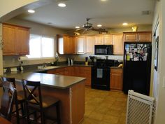 a kitchen with black appliances and wooden cabinets is seen from the doorway to the dining room