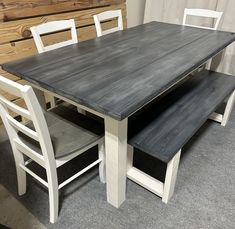 a wooden table with two benches next to it on carpeted floor in front of wood paneling