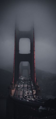 cars are driving over the golden gate bridge on a foggy day