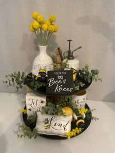 a three tiered tray with yellow flowers and items on it that say bee's knees