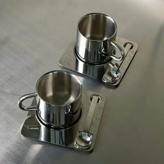 two stainless steel pots sitting on top of a table