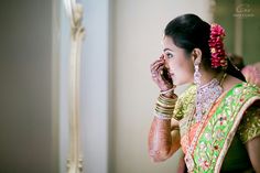 a woman in a green and orange sari is talking on her cell phone while looking into the mirror