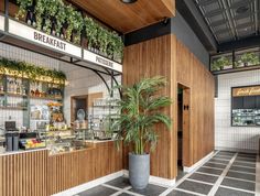 the inside of a restaurant with wooden walls and plants on the outside wall, along with tiled flooring