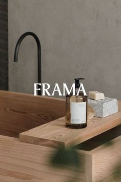 a bottle of soap sitting on top of a wooden table next to a faucet