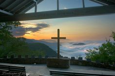 a cross on top of a hill overlooking the clouds