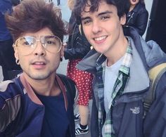 two young men taking a selfie in front of a group of people on the street