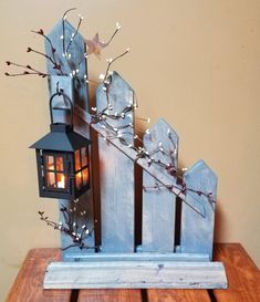 a wooden table topped with a lantern and a small bird on top of the fence