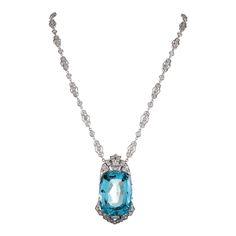 This stunning pendant was converted from an art deco era clip/brooch and is suspended from an attached diamond chain of more modern manufacture. The pendant is rendered in platinum with an 18 karat white gold back frame and the chain is 18 karat white gold. The elongated cushion faceted aqua boasts exceptional color for a stone of this size and weighs 51 carats. The major stone is accented by 2.72 carats of diamonds on the chain and set in the elaborate frame of the aqua. Bold, yet ultra-feminin Luxury Aquamarine Necklace In Fine Jewelry Style, Evening Platinum Pendant Necklace, Platinum Pendant Necklace For Evening, Art Deco Platinum Jewelry For Evening, Formal Diamond Necklace With Detachable Pendant, Formal Art Deco Jewelry With Large Pendant, Platinum Pendant Jewelry For Evening, Art Deco Pendant Necklace, Diamond Rings With Price