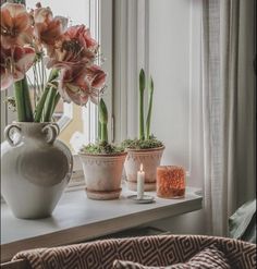 flowers are sitting on a window sill in front of a vase and candle holder