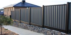 a stone wall next to a house with a metal fence on it's side