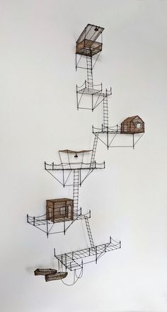 an artistic sculpture made out of wire and wood with multiple wooden houses on top of it