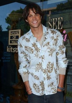 a man standing in front of a store with his hands in his pockets and smiling