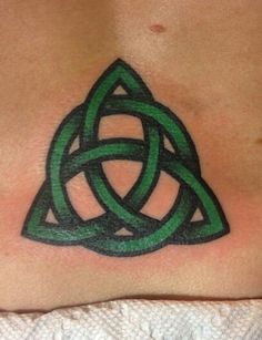 a green tattoo design on the back of a woman's chest, with two intertwined